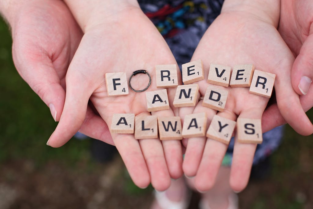 Hands holding 'forever and always' in Scrabble letters, symbolizing eternal love.