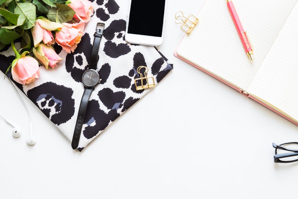 Drop Shipping Desk Stylish flat lay of office essentials including pink roses, watch, notebook, and accessories on white background.