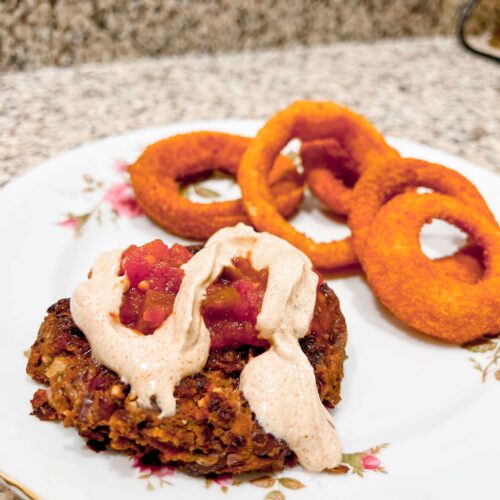 homemade black bean burger on a plate with onion rings