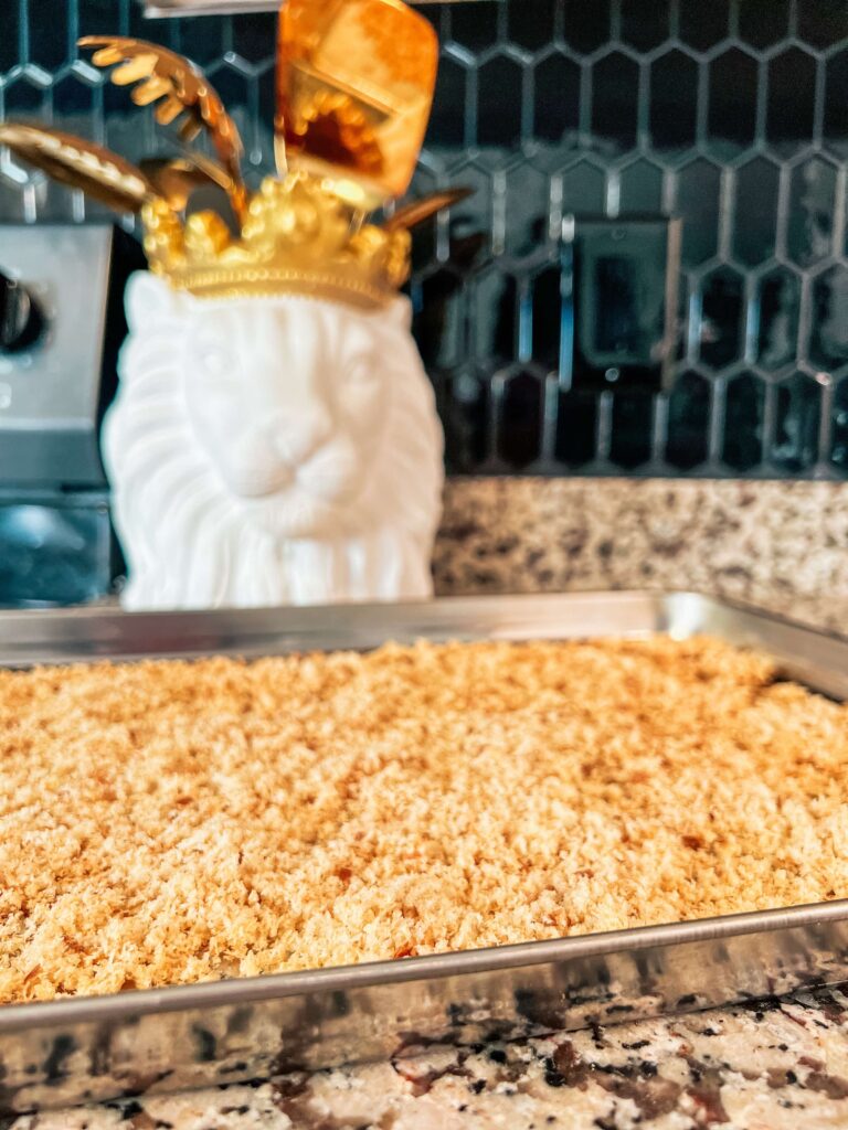 photo of breadcrumbs on a stainless steel baking sheet with a lion utensil holder in the background